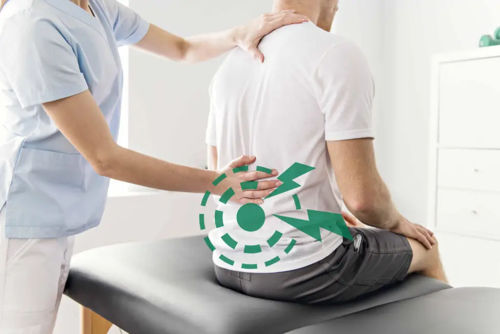 A lower back pain physiotherapist working on a client while he sits upright with the practitioners hands on him